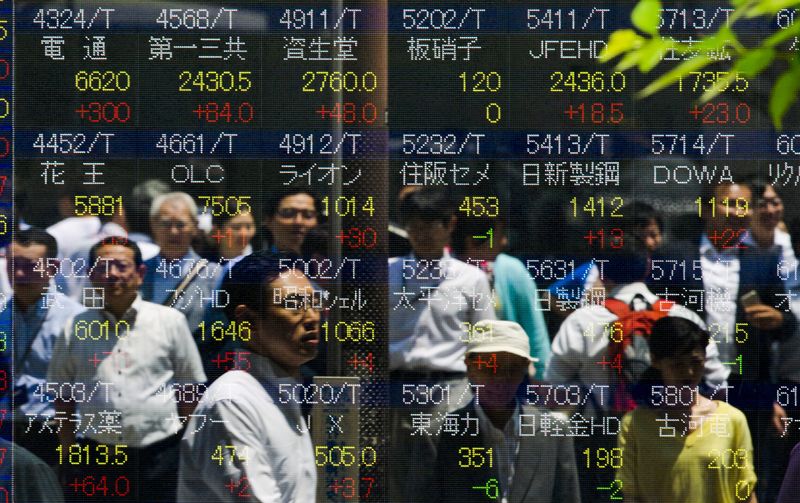 © Reuters. People are reflected in board displaying stock indices in Tokyo