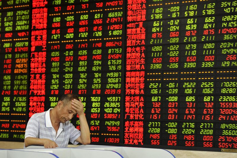 © Reuters. An investor looks at a computer screen in front of an electronic board showing stock information at a brokerage house in Fuyang