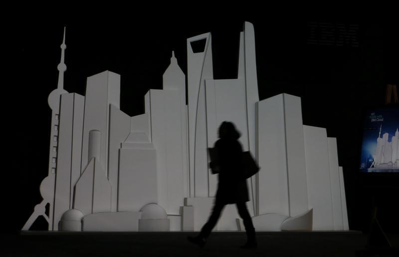 © Reuters. A person walks past an illuminated skyline at the booth of IBM at the CeBIT trade fair in Hanover