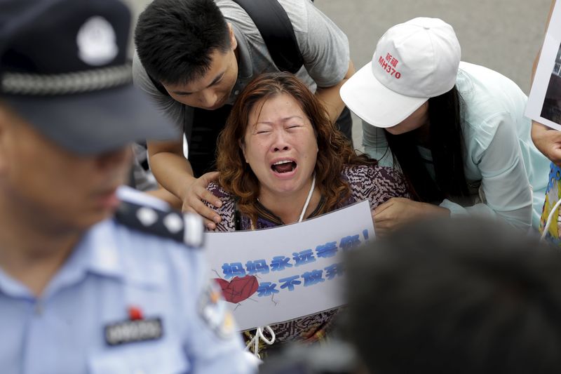 © Reuters. A woman cries as she other family members kneel down in front of media ahead of a briefing given by Malaysia Airlines in Beijing