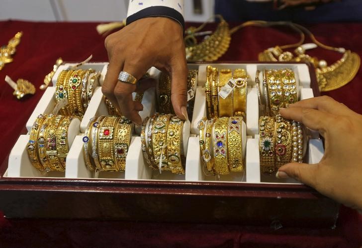 © Reuters. Продавец помогает покупателю выбрать золотой браслет в ювелирном магазине в Мумбаи