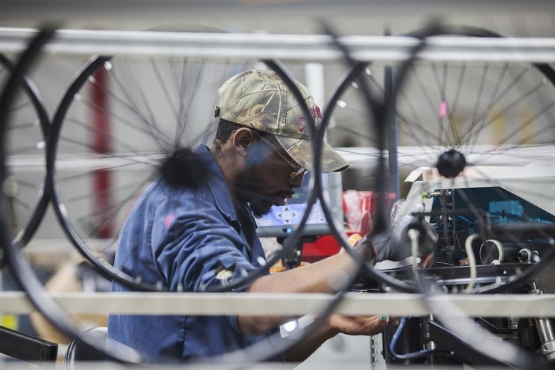 © Reuters. Employee Edward Klutz operates a wheel lacing machine at the new Bicycle Corporation of America plant in Manning