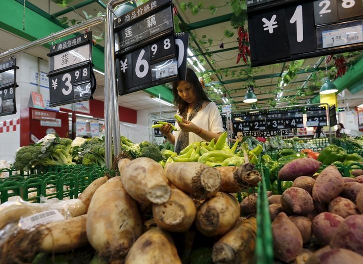 © Reuters. A woman chooses vegetables at a supermarket in Beijing