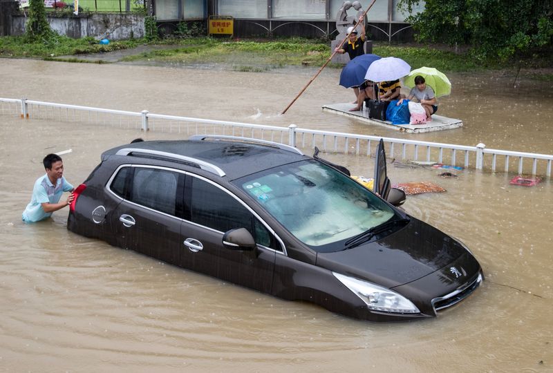 © Reuters. A trapped car is pushed along a flooded street after typhoon Soudelor hit Fuzhou