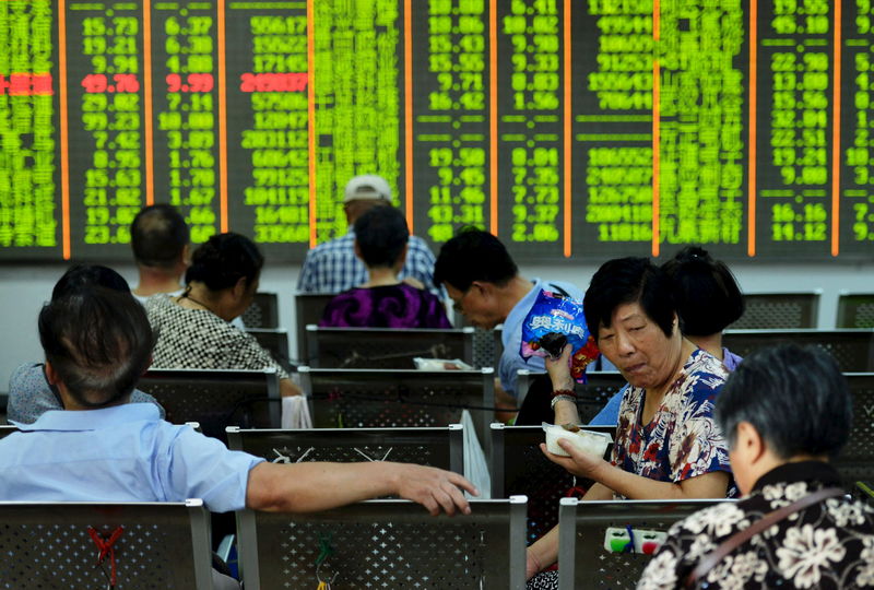 © Reuters. Investors have lunch in front of an electronic board showing stock information at a brokerage house in Hangzhou