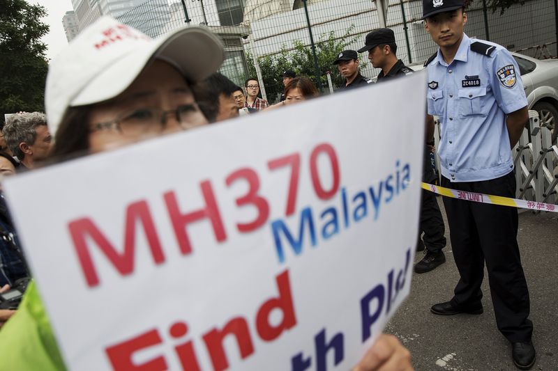 © Reuters. A woman whose relative was aboard Malaysia Airlines flight MH370 holds placard after police stopped protesting relatives from entering a road leading to the Malaysian embassy in Beijing