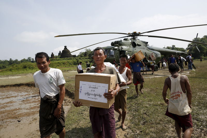 © Reuters. Storm victims carry aid from a military helicopter at Mrauk-U township, Rakhine state 