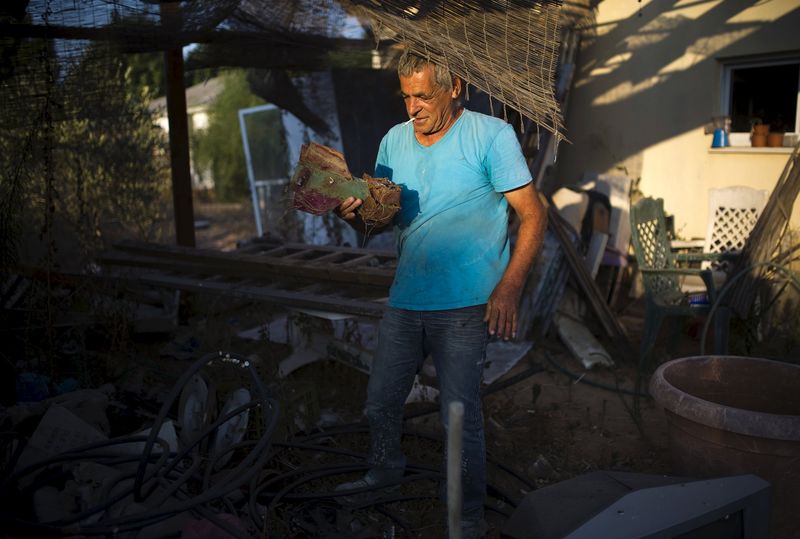 © Reuters. Israeli Nahum Hadad holds the remains of a rocket that he said landed near his former home in the Jewish settlement of Nisanit in Gaza, as he stands outside his home in Nitzan near Ashod, Israel