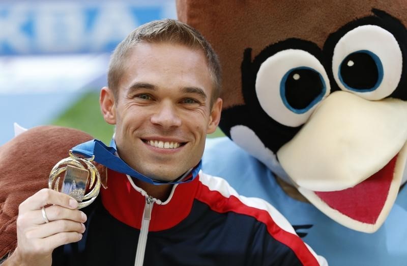 © Reuters. Silver medallist Symmonds of the U.S. poses with mascot after victory ceremony for men's 800 metres at World Athletics Championships in Moscow