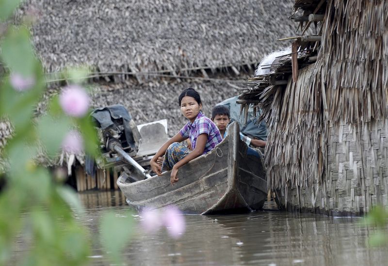 © Reuters. People sit on a boat near their home in a flooded village outside Zalun Township, Irrawaddy Delta