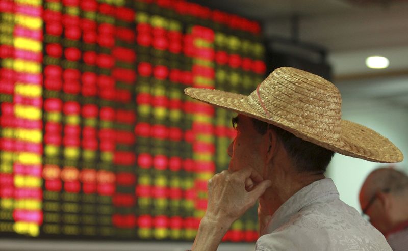 © Reuters. Homem olhando painel de cotações da bolsa de valores em Haikou, na China