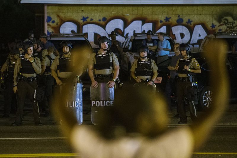 © Reuters. St Louis County police officers watch as anti-police demonstrators march in protest in Ferguson, Missouri