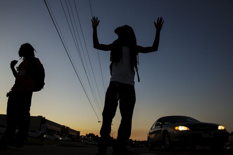 © Reuters. A man gestures on the side of West Florissant Ave. as a much smaller group of demonstrators prepare to protest for another night in Ferguson, Missouri 