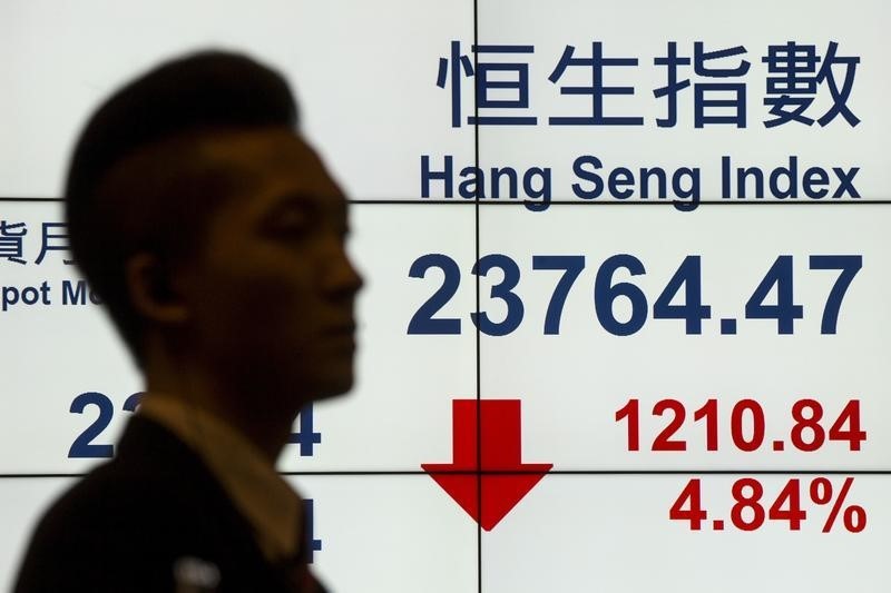 © Reuters. A man walks past a panel displaying the Hang Seng Index at the Hong Kong Exchanges in Hong Kong, China 