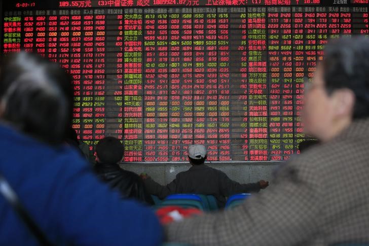 © Reuters. Investors look on in front of an electronic board showing stock information at a brokerage house in Shanghai