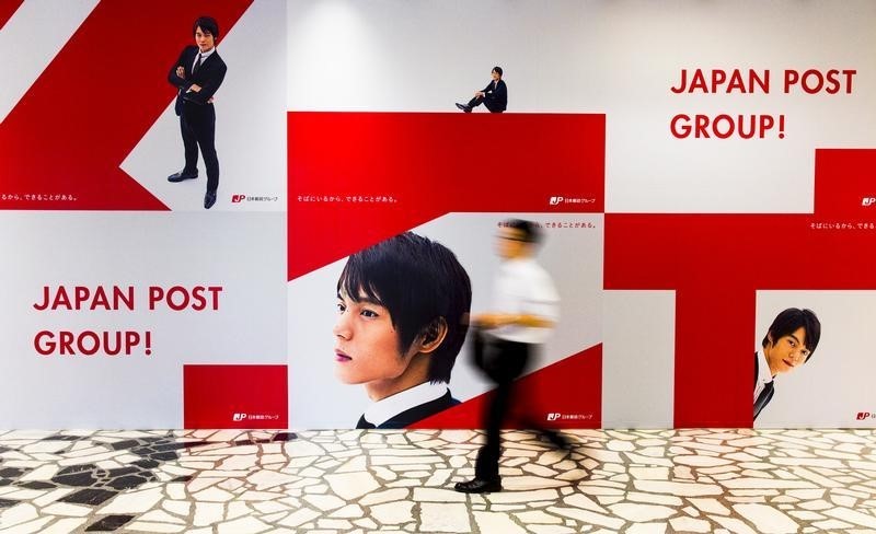 © Reuters. Man walks past advertising poster in headquarters of Japan Post  in Tokyo