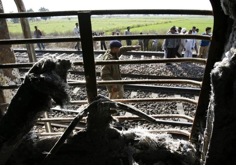 © Reuters. Onlookers stand near a burnt carriage of Samjhauta Express train in Deewana near Panipat town