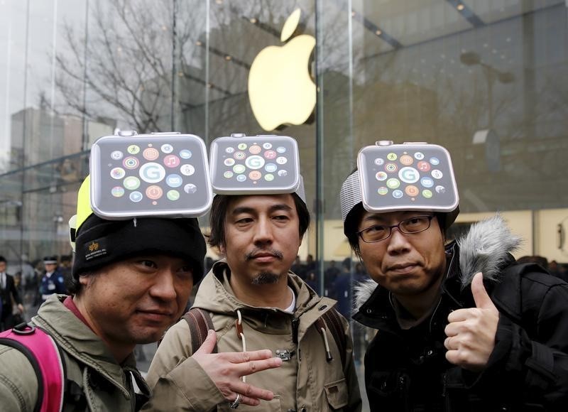 © Reuters. Men wearing cardboard hats depicting the Apple Watch, pose for photos before it goes on display in front of the Apple Store in Tokyo's Omotesando shopping district