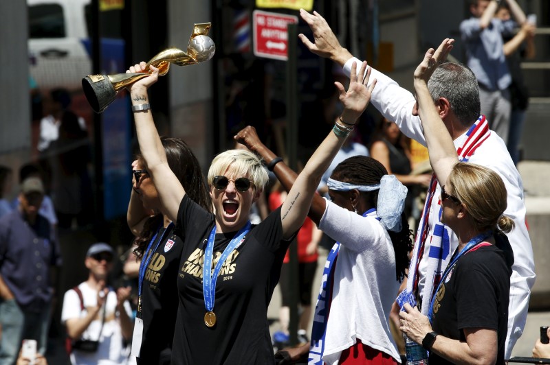 © Reuters. U.S. women's soccer player Rapinoe holds the Wold Cup trophy as she rides a float with team mate Lloyd during the ticker tape parade, in New York