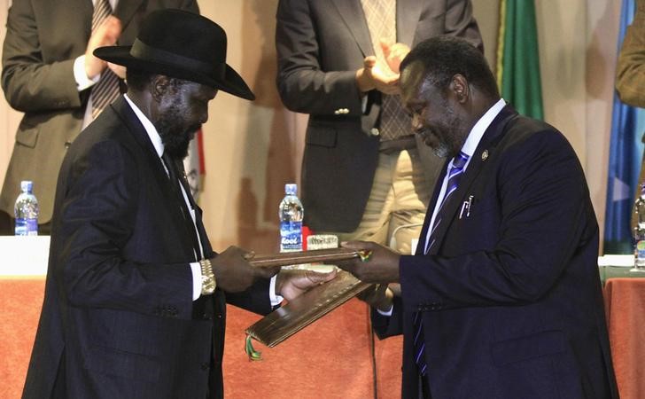 © Reuters. South Sudan's President Kiir and rebel commander Machar exchange documents after signing a ceasefire agreement during the IGAD Summit on the case of South Sudan in Addis Ababa