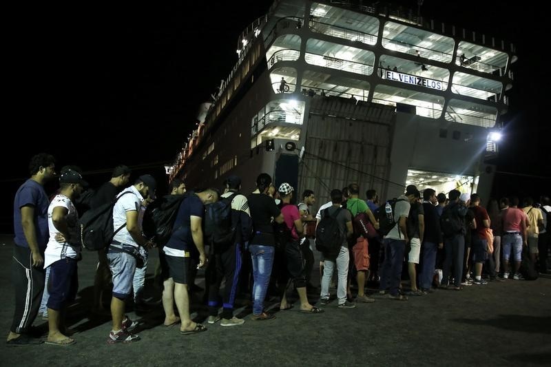 © Reuters. سوريون يبدأون ركوب سفينة للاجئين في جزيرة يونانية