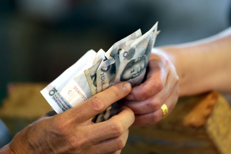 © Reuters. A vendor gives change of 10 Yuan notes to a customer in Beijing