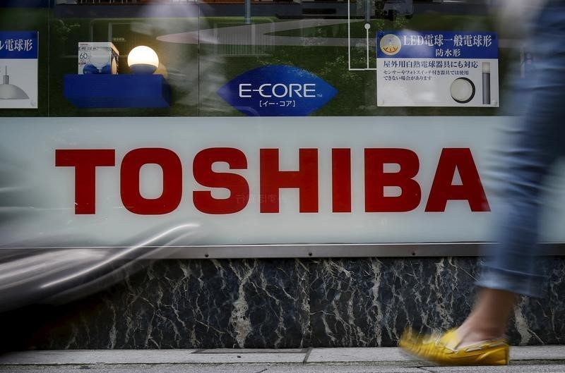 © Reuters. Pedestrians walk past a logo of Toshiba Corp outside an electronics retailer in Tokyo