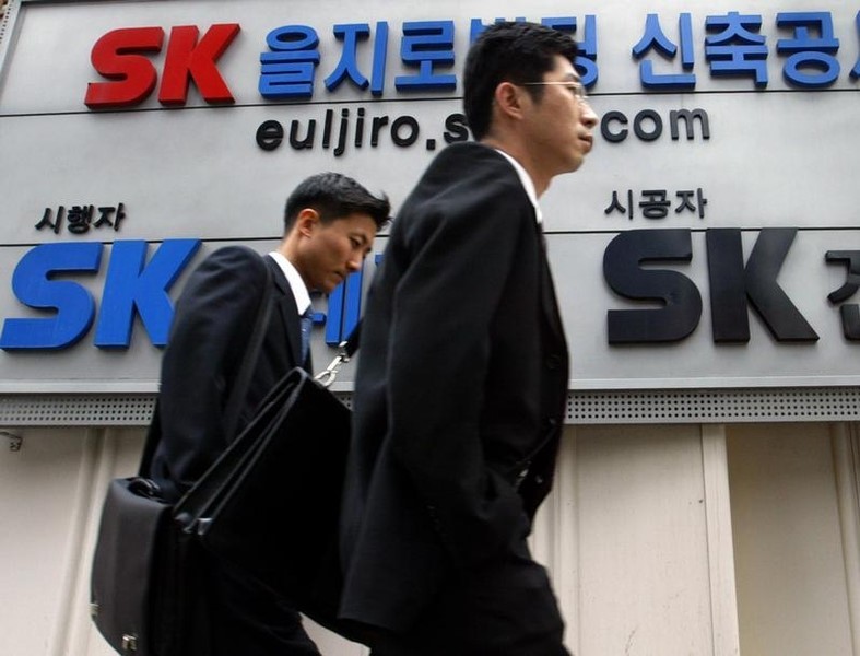© Reuters. SOUTH KOREANS WALK PAST THE LOGO OF SK GROUP IN SEOUL.