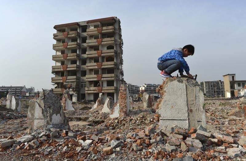 © Reuters. A boy plays on a broken wall next to a partially demolished building at a demolition site making way for a new residential area, in Hefei