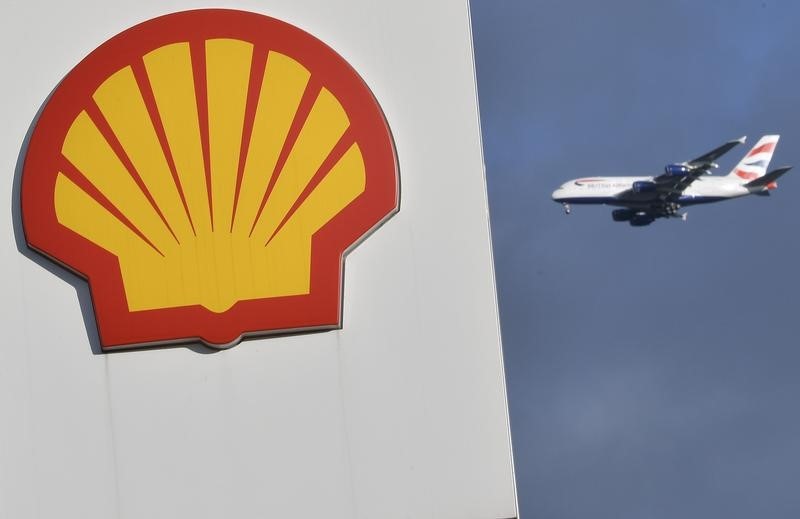 © Reuters. A passenger plane flies behind a Shell logo at a petrol station in west London