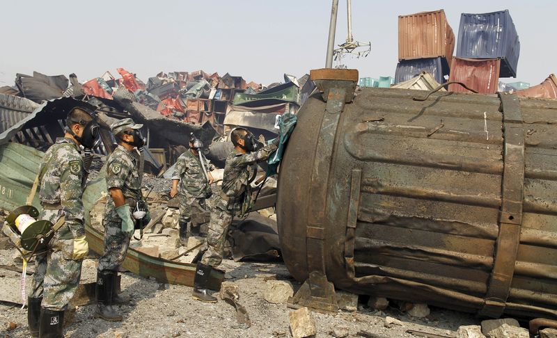 © Reuters. Soldiers of People's Liberation Army anti-chemical warfare corps examine a container at the site of Wednesday night's explosions at Binhai new district