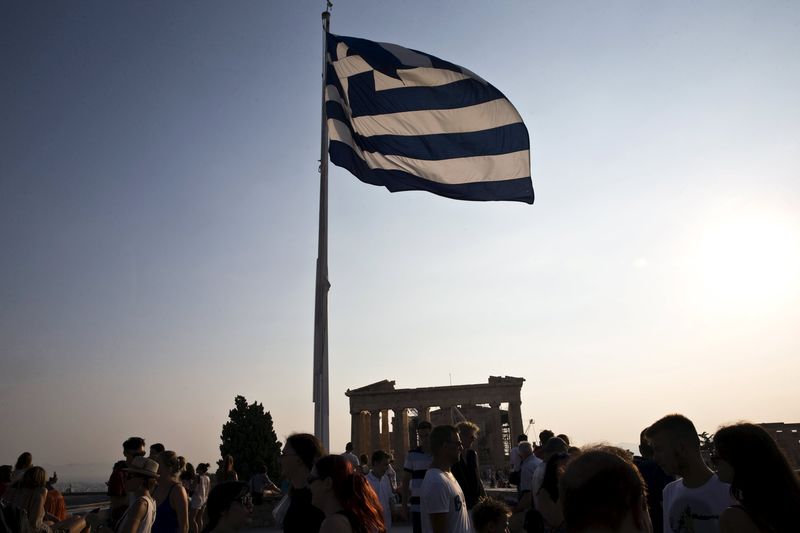 © Reuters. Greek flag flutters in the wind above tourists visiting the archaeological site of the Acropolis hill in Athens, Greece