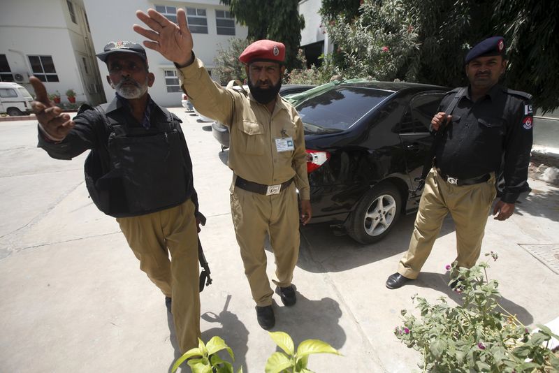 © Reuters. Police officers stop media from going near the car of Abdul Rashid Godil, a member of the Muttahida Qaumi Movement after he was shot, at a hospital in Karachi