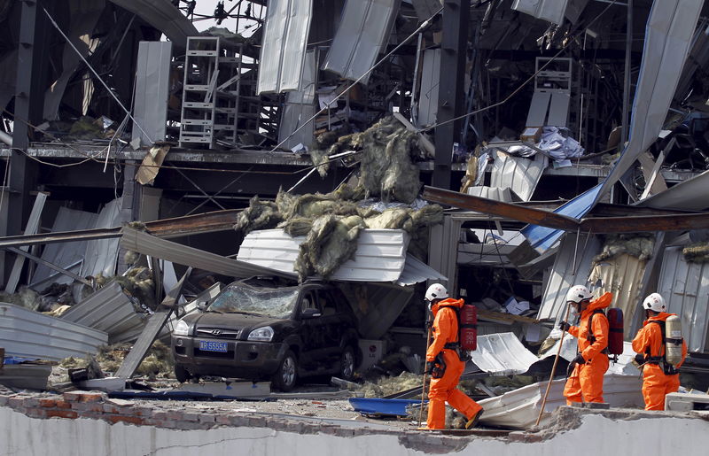 © Reuters. Bombeiros em meio a destroços após explosões em Tianjin, na China