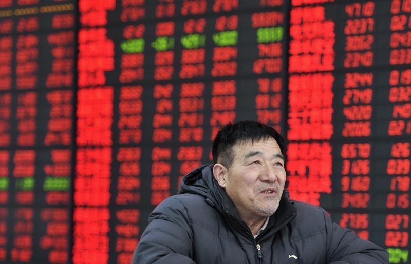 © Reuters. An investor looks on in front of an electronic board showing stock information at a brokerage house in Fuyang
