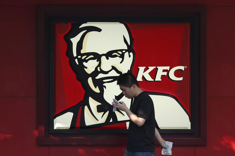 © Reuters. A man walks past a logo of KFC, outside a restaurant in Shanghai