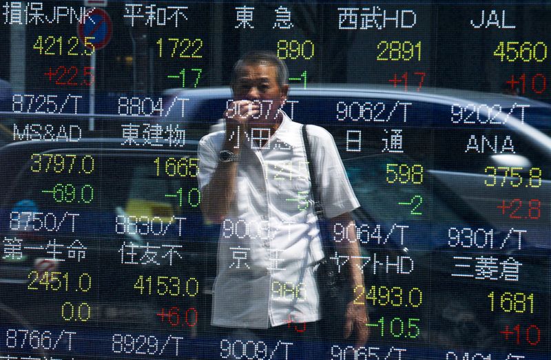 © Reuters. A man looks at stock prices displayed at a board showing market indices in Tokyo