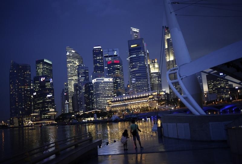© Reuters. People take photos with the skyline of the financial district of Singapore in the background