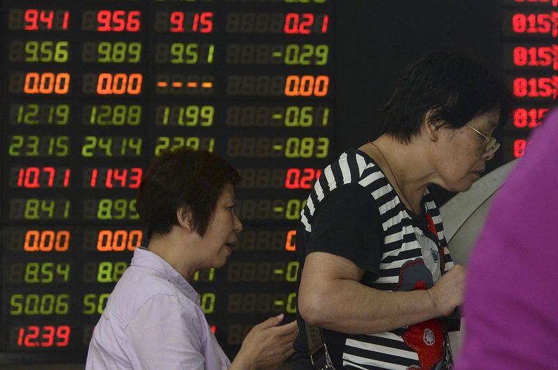 © Reuters. Investors look at computer screens in front of an electronic board showing stock information at a brokerage house in Shanghai