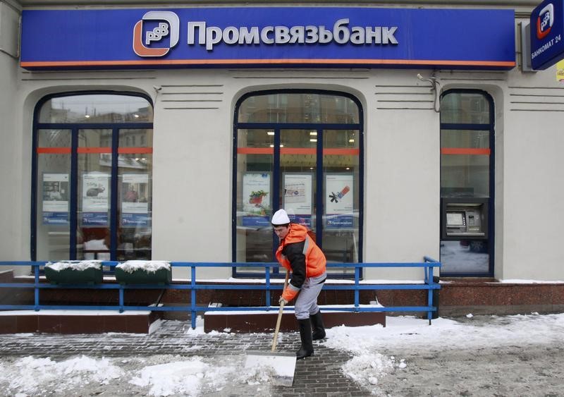 © Reuters. A man shovels snow in front of an office of Promsvyazbank in Moscow