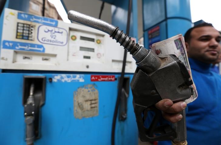 © Reuters. An employee holds up a fuel pump nozzle after filling up a car at a CO-OP gas station in Cairo