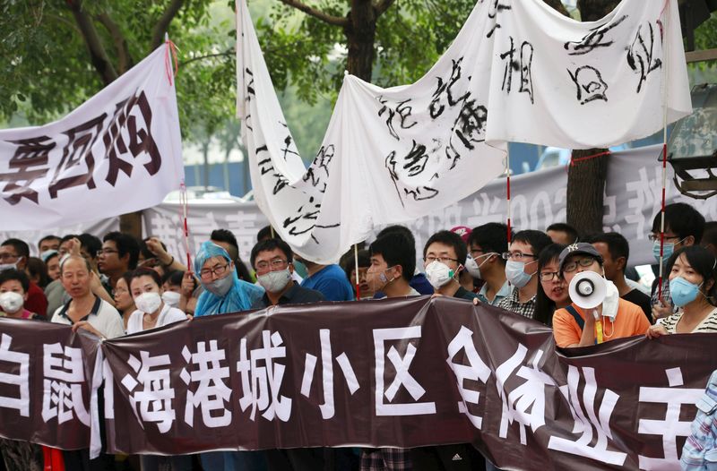 © Reuters. Residents evacuated from their homes after last week's explosions in Binhai new district take part in a rally outside a government officials' news conference venue in Tianjin