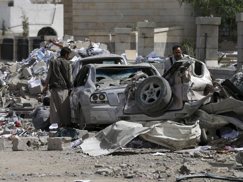 © Reuters. People check the wreckage of cars destroyed by Saudi-led air strikes on the nearby offices of the education ministry's workers union in Yemen's northwestern city of Amran