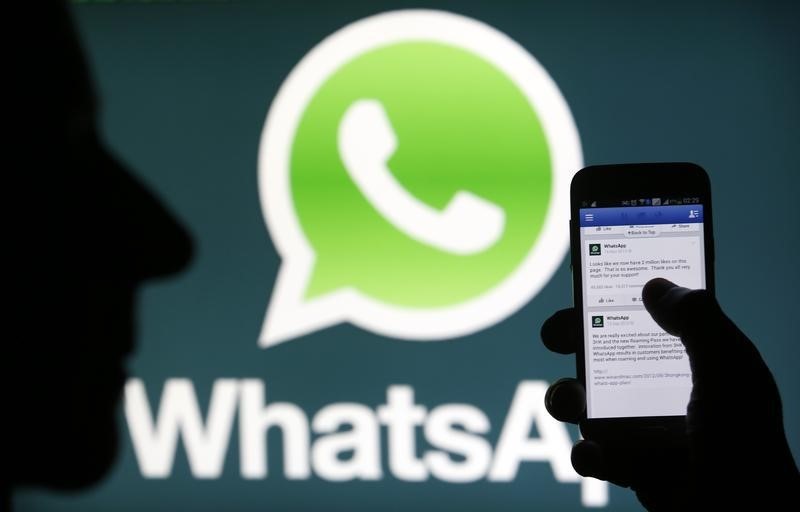 © Reuters. Logotipo do aplicativo Whatsapp é visto atrás de aparelho móvel de usuário navegando no Facebook.