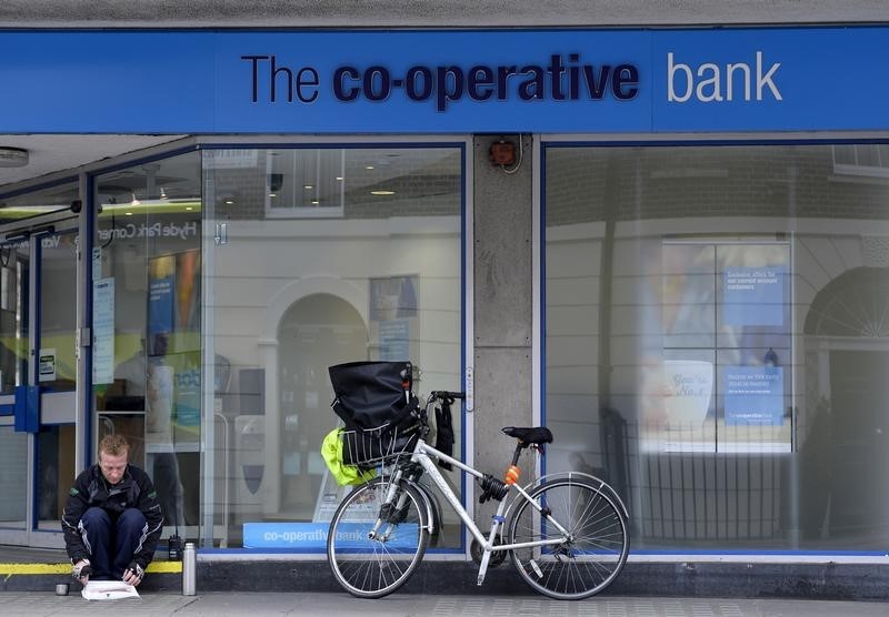 © Reuters. A man reads a newspaper outside a branch of the Co-operative bank in central London