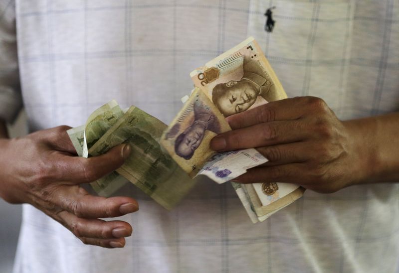 © Reuters. A customer counts Chinese Yuan notes at a market in Beijing