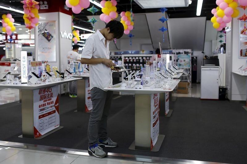 © Reuters. A customer look at a mobile phone on display at an electronics market in Shanghai