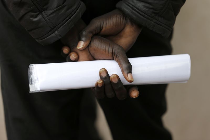 © Reuters.  A migrant who seeks asylum holds documents as he gathers outside the Sous-Prefecture building in Calais