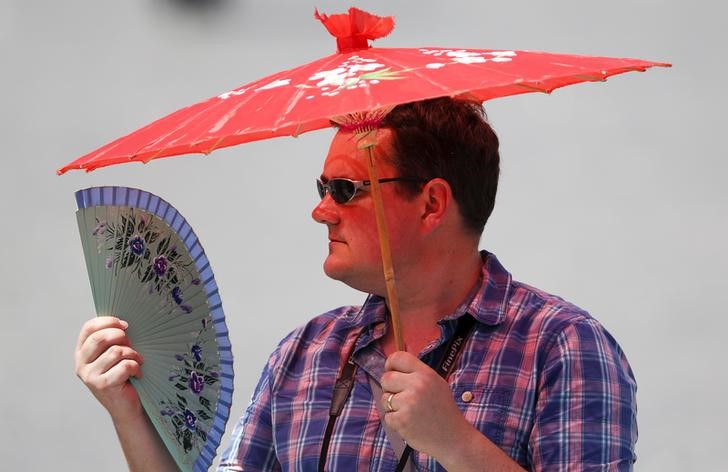 © Reuters. Homem se protege do sol e do calor na praça de São Pedro no Vaticano