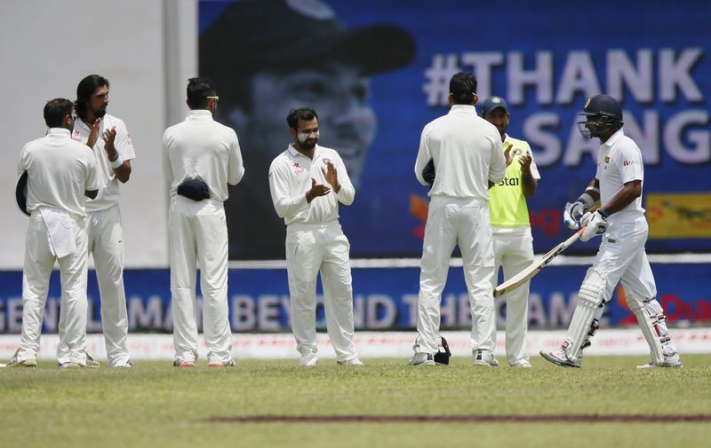 © Reuters. Indian cricket team members stand in a line as Sri Lanka's Sangakkara arrives on the ground during the second day of their second test cricket match against India in Colombo